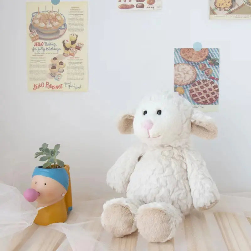 weiches süßes weißes sitzendes Plüschschaf