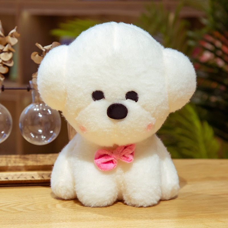 This image shows a cute sitting Bichon Frise Stuffed Animal Plush Toy with a black collar-bell in it's neck and sitting on the table.