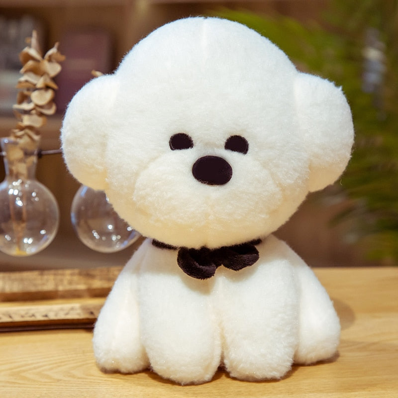 This image shows a cute Bichon Frise Stuffed Animal Plush Toy with a grass on it's head and sitting on the table.